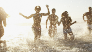 Barn som springer i vatten vid strand.