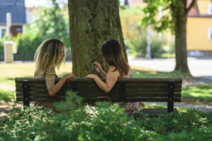 Två flickor som sitter på en bänk